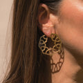 Håndlavede geometriske hoop øreringe i 24 karat forgyldt sølv fra Afghanistan, inspireret af Girih-mønstre fra persisk og islamisk kunst. Båret af model i naturligt lys, der fremhæver øreringens elegante design og skyggeeffekt.