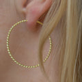 Håndlavede snoede hoops i 24 karat forgyldt sølv fra Afghanistan, inspireret af det persiske Laleh-design. Båret af model, der viser øreringens elegante og lette udtryk.
