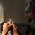 Håndvævet tæppe i proces, skabt af en kvindelig håndværker i Afghanistan. Detaljeret væveteknik og traditionelle mønstre fremhævet i naturligt lys.